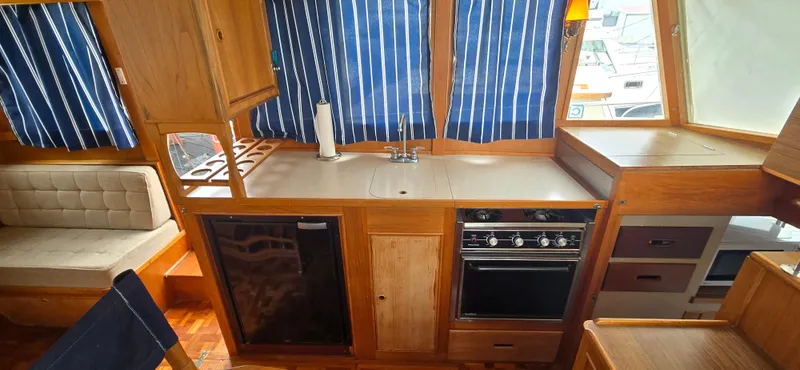 Interlude Yacht Photos Pics 1987 Grand Banks 36 Classic yacht interior with kitchen, stove, and striped curtains.