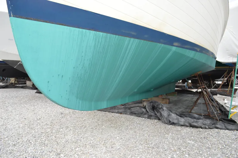 Interlude Yacht Photos Pics 1987 Grand Banks 36 Classic boat hull on gravel, turquoise and white colors.