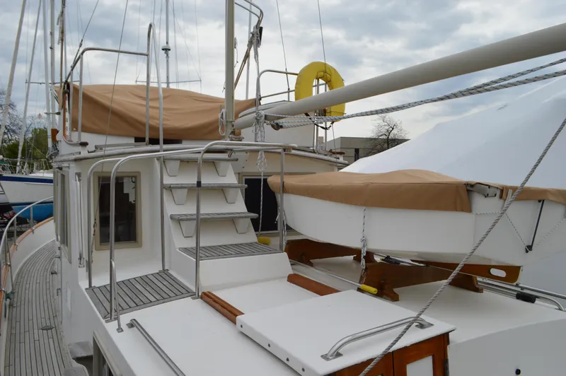 Interlude Yacht Photos Pics 1987 Grand Banks 36 Classic yacht with covered deck and lifeboat, docked under cloudy skies.