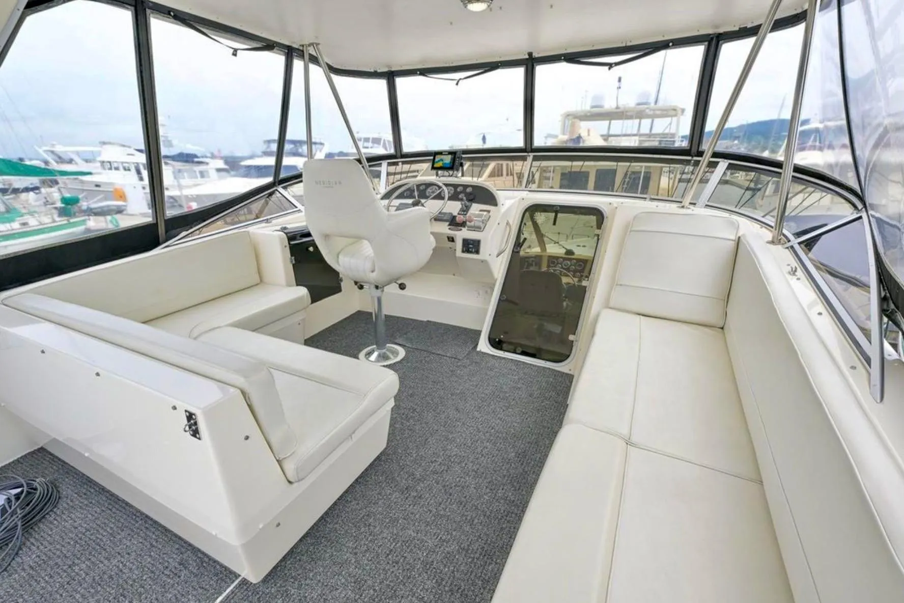 2004 Meridian 490 Pilothouse interior with white seating and helm, docked at marina.
