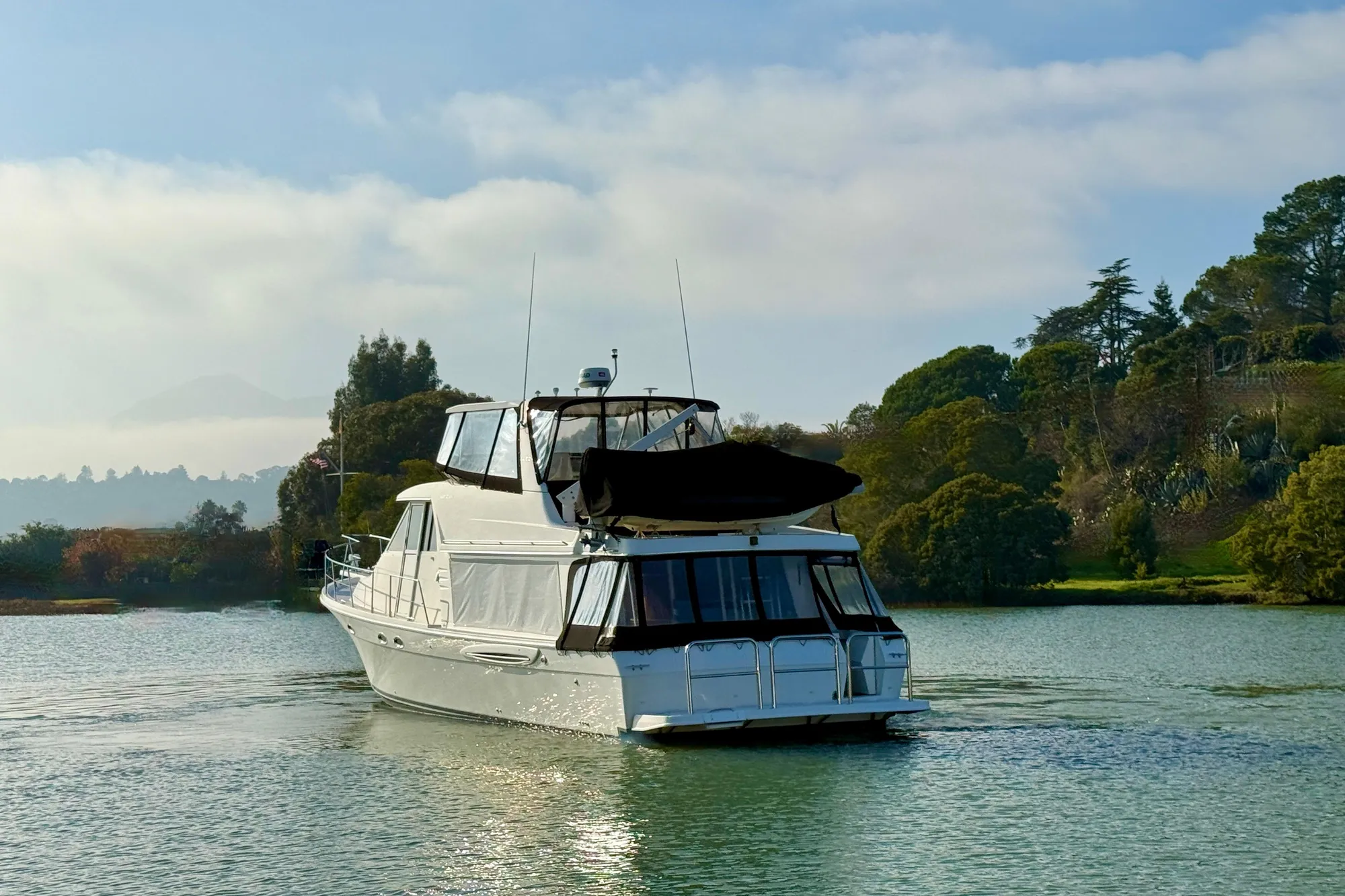 Meridian 490 Pilothouse 2004 on calm water with wooded backdrop.