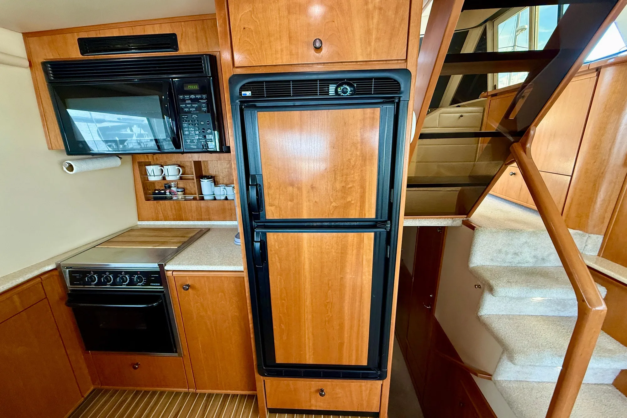 2004 Meridian 490 Pilothouse kitchen with wood cabinetry, appliances, and stairs.