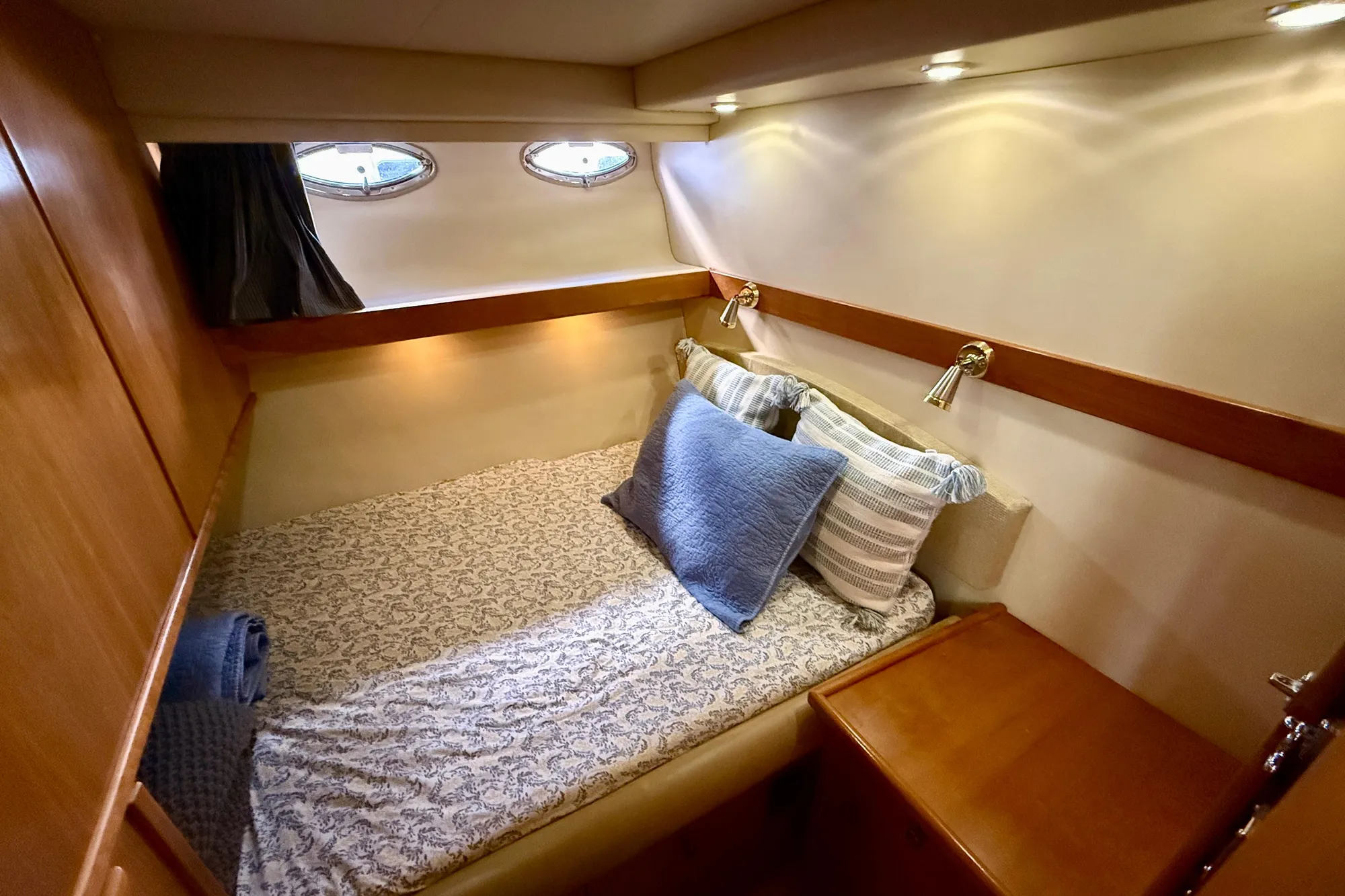 Cozy cabin interior of 2004 Meridian 490 Pilothouse with bed and portholes.