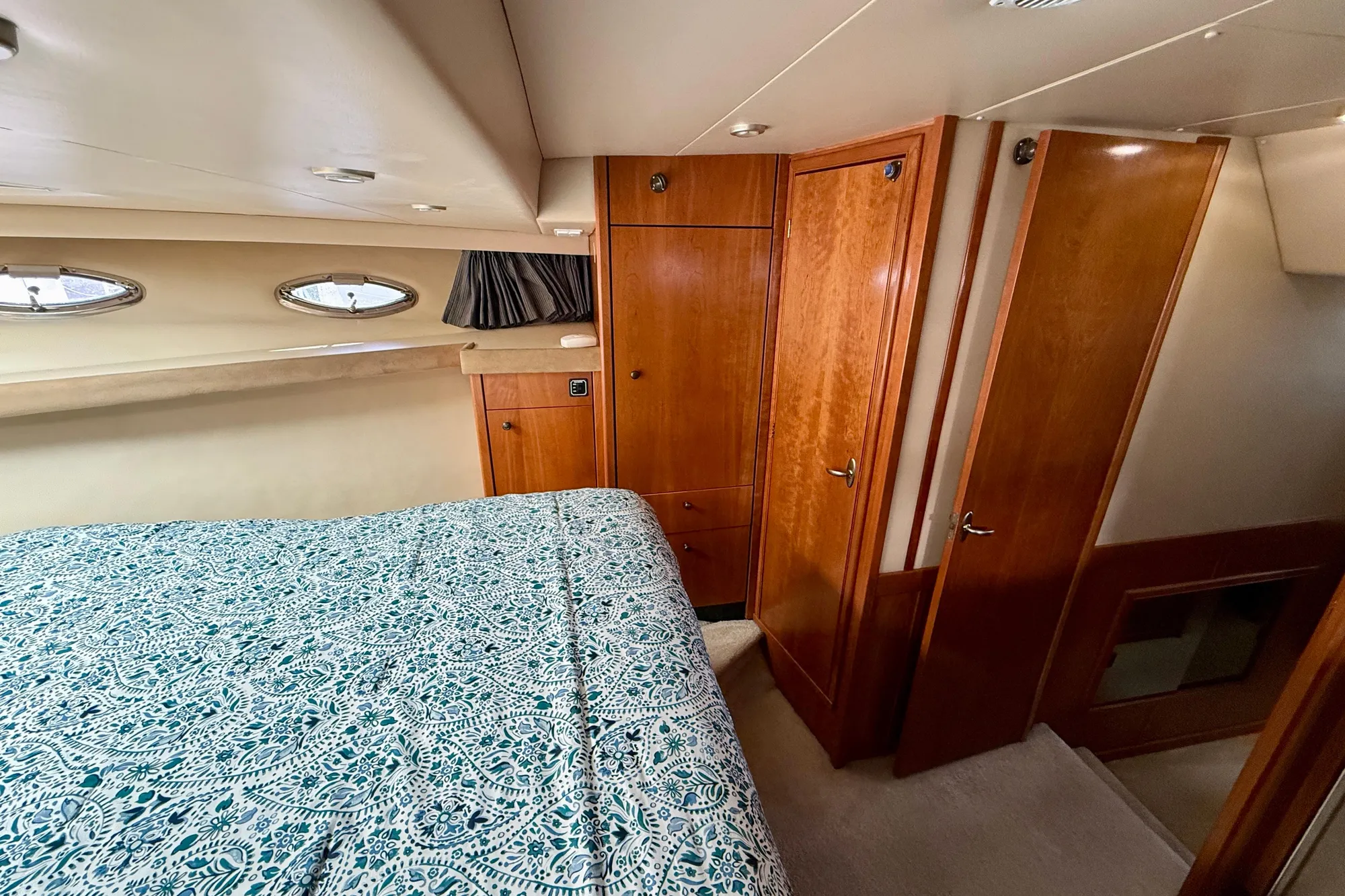 Luxurious cabin interior of 2004 Meridian 490 Pilothouse yacht with wood finish and patterned bedding.