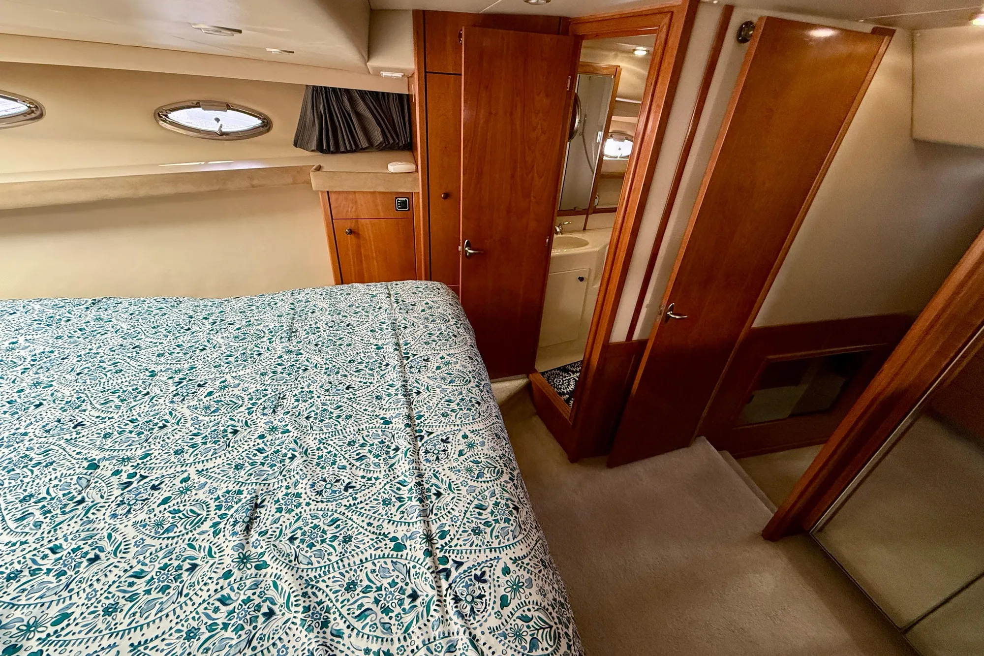 Luxurious 2004 Meridian 490 Pilothouse bedroom with patterned bedding and wooden cabinetry.