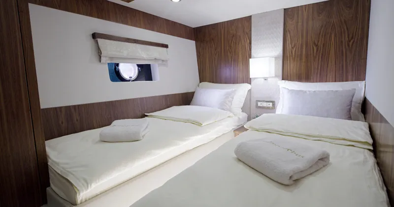 Panta Rei Yacht Photos Pics Luxurious twin cabin in 2022 Monachus 70 Fly yacht, featuring elegant wood paneling and cozy bedding.