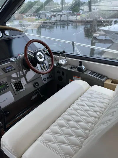 Rough Play Yacht Photos Pics 2010 Regal 600 Express helm with leather seating and wooden steering wheel, docked by the water.