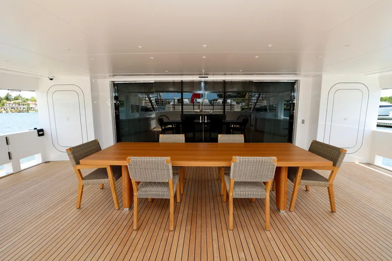  Yacht Photos Pics Luxurious deck dining area on 2024 Rossinavi 49M Sport Yacht, featuring elegant wooden table and chairs.