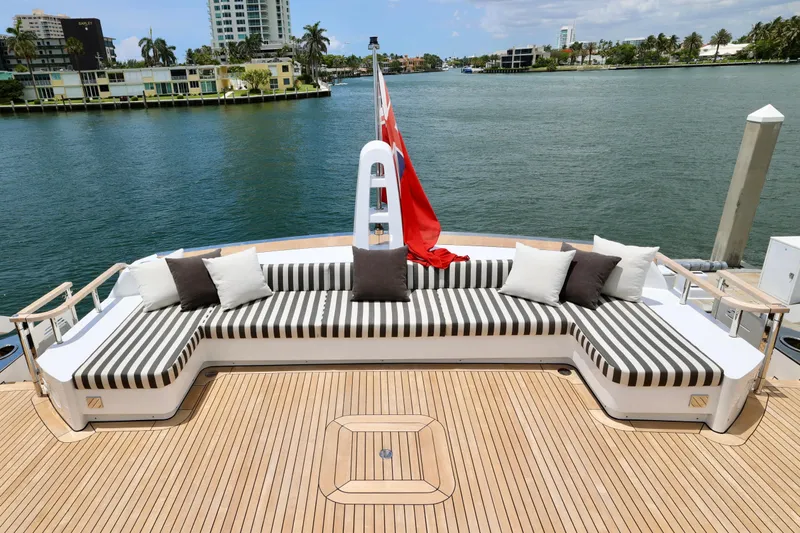 Yacht Photos Pics Luxurious deck of 2024 Rossinavi 49M Sport Yacht with striped seating and scenic waterfront view.