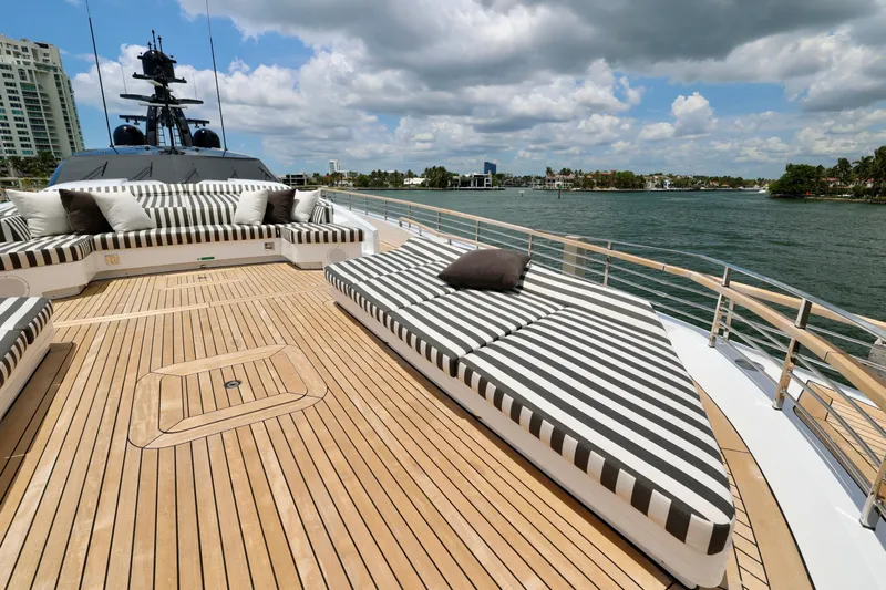  Yacht Photos Pics Luxurious 2024 Rossinavi 49M Sport Yacht deck with striped sun loungers and scenic waterfront view.