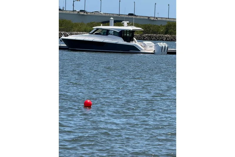  Yacht Photos Pics 2025 Tiara Yachts 48 LE docked on calm water with a red buoy nearby.