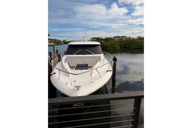  Yacht Photos Pics 2025 Tiara Yachts 48 LE docked on a calm river under a partly cloudy sky.