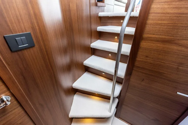 Twin Magic Yacht Photos Pics Luxurious interior staircase of 2025 Princess F50 yacht with wooden finish and soft lighting.