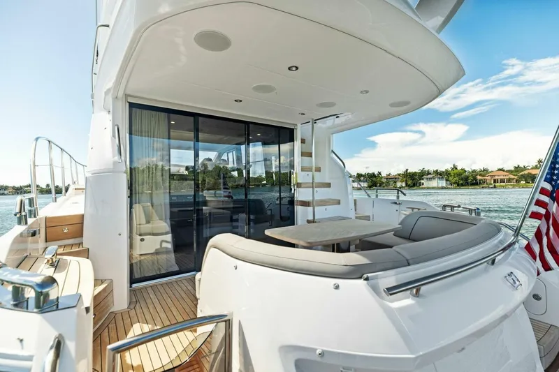 Twin Magic Yacht Photos Pics Luxurious 2025 Princess F50 yacht deck with seating, table, and scenic waterfront view.