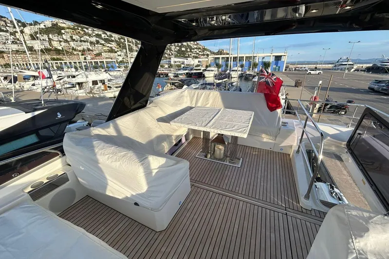  Yacht Photos Pics Luxurious 2023 Prestige 590 yacht deck with seating, table, and marina view.