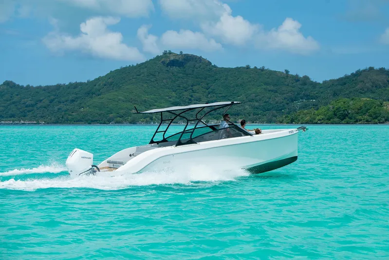  Yacht Photos Pics 2025 Rand Supreme 27 boat cruising on turquoise water with lush green hills in the background.