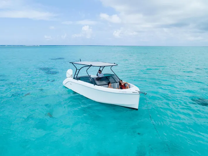  Yacht Photos Pics A 2025 Rand Supreme 27 boat on clear turquoise water under a partly cloudy sky.