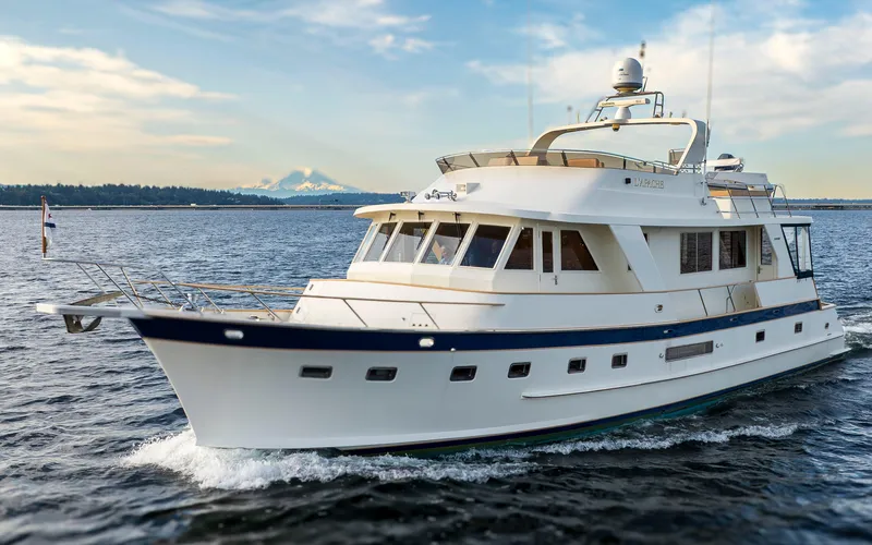 L'apache Yacht Photos Pics Luxury 2006 Alaskan 65 Flushdeck yacht cruising on open water, scenic mountain backdrop.