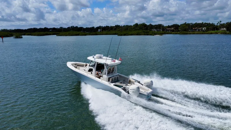 Mermaiden Yacht Photos Pics 2020 Solace 345 boat speeding on a scenic lake under a cloudy sky.