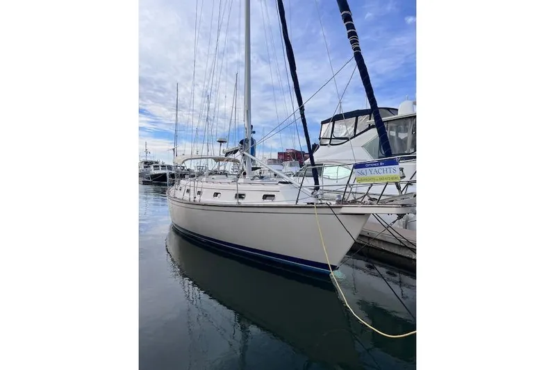 Dream Flower Yacht Photos Pics 1995 Island Packet 40 sailboat docked in marina, clear sky reflection on water.