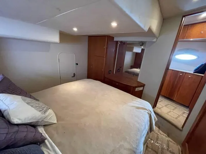  Yacht Photos Pics Interior of 2000 Silverton 453 Motor Yacht bedroom with bed, wooden cabinets, and soft lighting.
