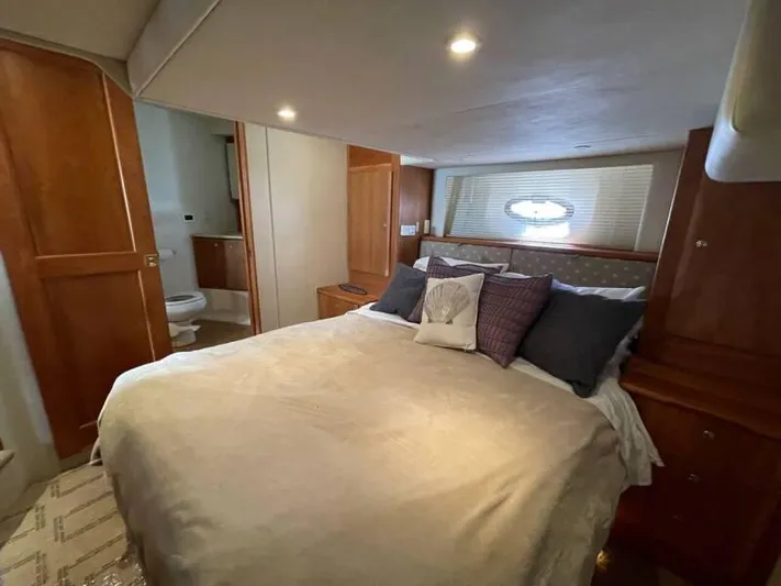  Yacht Photos Pics 2000 Silverton 453 Motor Yacht bedroom with cozy bed, wooden cabinetry, and ensuite bathroom.
