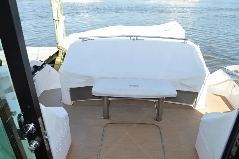 Andros Yacht Photos Pics 2016 Tiara Yachts C44 Coupe aft deck with covered seating and table, overlooking water.