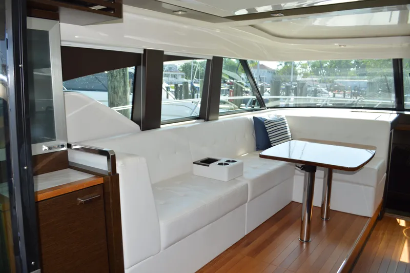 Andros Yacht Photos Pics Luxurious interior of 2016 Tiara Yachts C44 Coupe with white seating and wooden table.