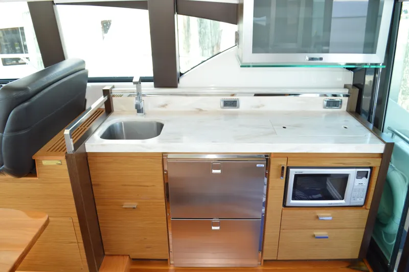 Andros Yacht Photos Pics Modern kitchen area in 2016 Tiara Yachts C44 Coupe with sink, microwave, and storage.