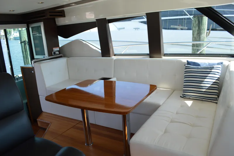 Andros Yacht Photos Pics Interior of 2016 Tiara Yachts C44 Coupe with white seating and wooden table.