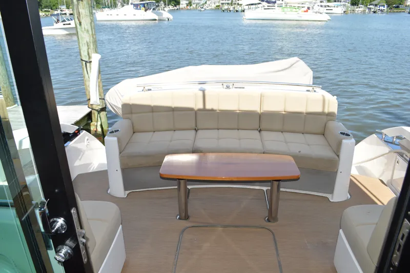 Andros Yacht Photos Pics 2016 Tiara Yachts C44 Coupe interior with beige seating and wooden table, docked by the water.