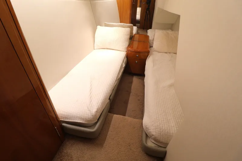  Yacht Photos Pics 2004 Hatteras 54 Convertible cabin with twin beds and wooden nightstand.