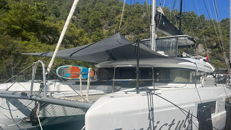  Yacht Photos Pics 2019 Lagoon 50 catamaran docked, featuring a sunshade and paddleboard, surrounded by lush greenery.