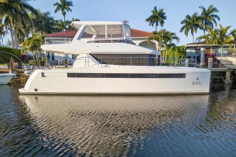  Yacht Photos Pics 2024 Leopard 46 Powercat yacht docked by palm trees and waterfront homes.