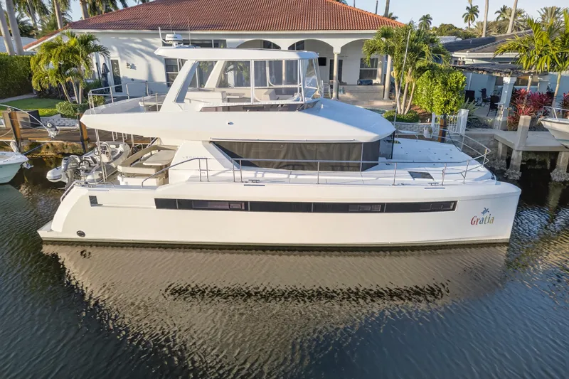  Yacht Photos Pics 2024 Leopard 46 Powercat yacht docked by a waterfront home, surrounded by tropical greenery.