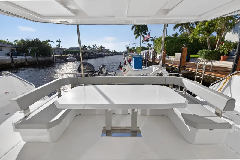  Yacht Photos Pics 2024 Leopard 46 Powercat yacht with outdoor seating, docked by a scenic waterfront.