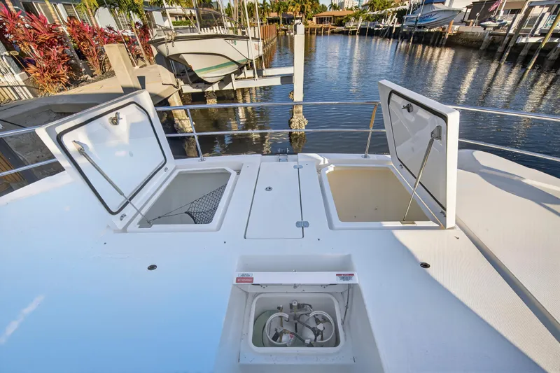  Yacht Photos Pics 2024 Leopard 46 Powercat deck with open storage compartments, docked by the water.