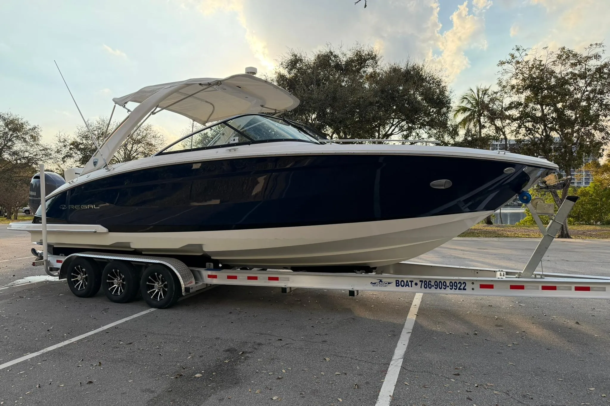 2019 Regal 29 OBX boat on trailer in parking lot, surrounded by trees.
