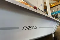 2023 Beneteau First 14 sailboat in showroom, side view with branding visible.