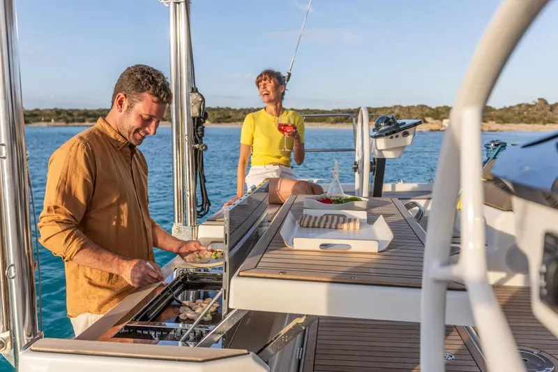  Yacht Photos Pics Couple enjoying a barbecue on a 2025 Dufour 48 yacht, with scenic ocean views.