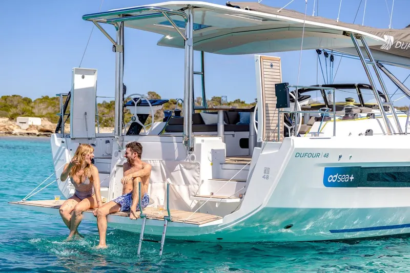  Yacht Photos Pics Couple relaxing on a 2025 Dufour 48 yacht in clear blue waters.