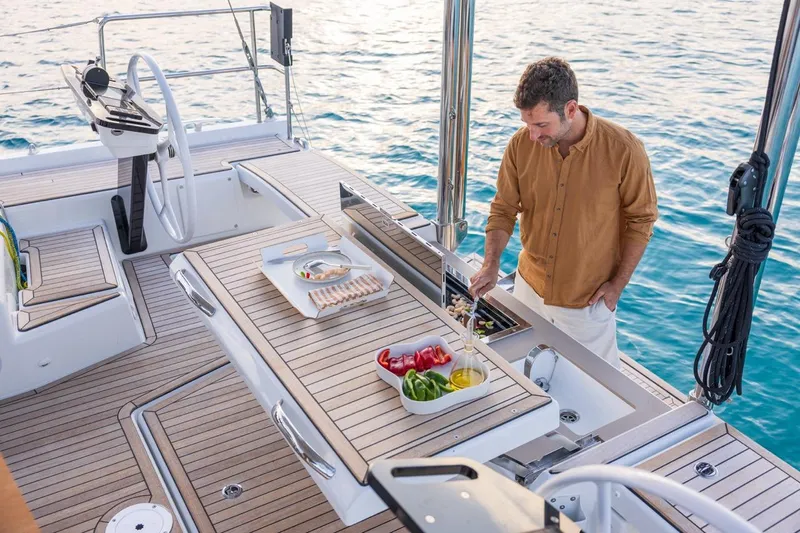  Yacht Photos Pics Man cooking on 2025 Dufour 48 yacht deck with ocean view.