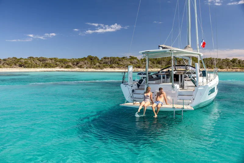  Yacht Photos Pics Couple relaxing on a 2025 Dufour 48 yacht in clear turquoise waters.