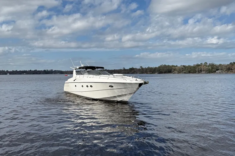  Yacht Photos Pics 1994 Sunseeker Camargue 55 yacht cruising on a calm lake under a partly cloudy sky.
