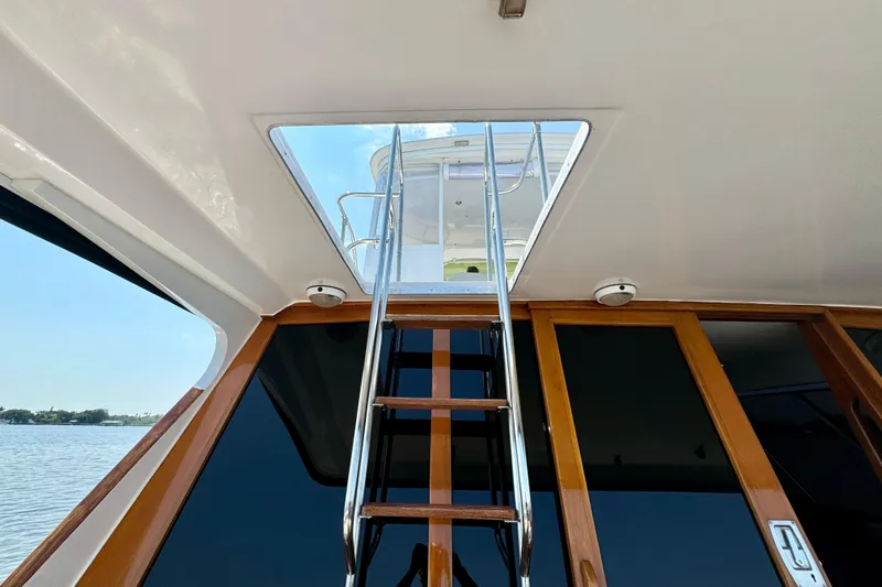 Perseverance Yacht Photos Pics 1989 Bayliner 4588 Motoryacht interior with ladder to upper deck, wooden doors, and water view.