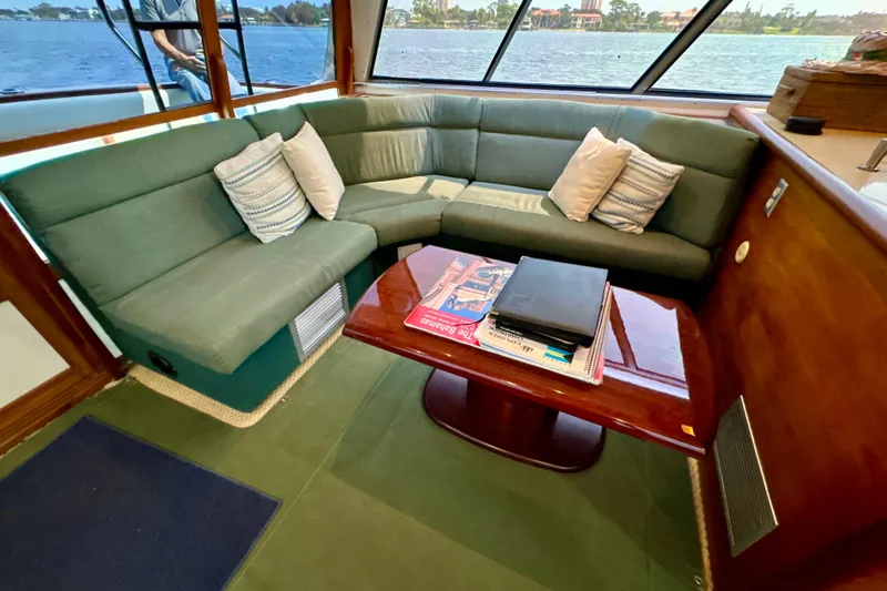 Perseverance Yacht Photos Pics 1989 Bayliner 4588 Motoryacht interior with green seating, wooden table, and scenic water view.