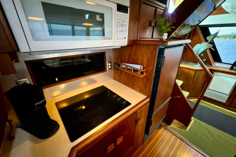 Perseverance Yacht Photos Pics 1989 Bayliner 4588 Motoryacht kitchen with microwave, stovetop, and wooden cabinetry.