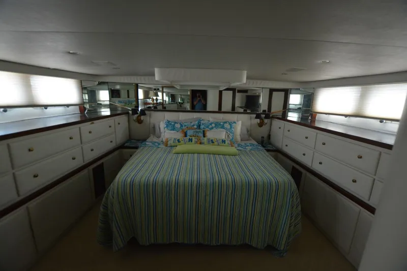 Unique Skill Yacht Photos Pics Luxurious bedroom interior of 1989 Hatteras Cockpit Motoryacht with striped bedding and ample storage.