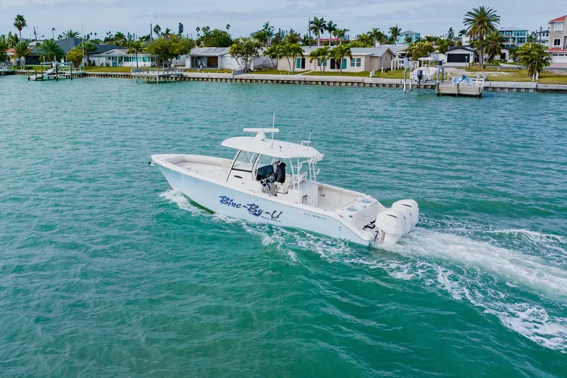 Yacht Photos Pics 2017 Cobia 344 Center Console boat cruising on turquoise water near coastal homes.