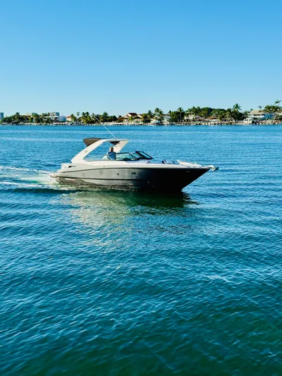  Yacht Photos Pics 2020 Monterey 328 SS boat cruising on clear blue water near a coastal shoreline.
